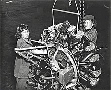 Two Marine Corps women repairing an airplane engine