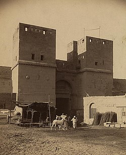 Sepia-tinted photograph of a medieval gate with large towers