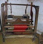 Handloom at Hjerl Hede, Denmark, showing grayish warp threads (back) and cloth woven with red filling yarn (front)