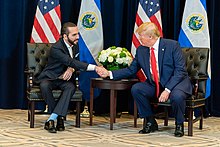 Nayib Bukele and Donald Trump sitting down and shaking hands
