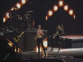 Panic! at the Disco at the Pepsi Center in 2018. From left to right: Kenneth Harris (guitar), Dan Pawlovich (drums), Brendon Urie (vocalist), and Nicole Row (bass)