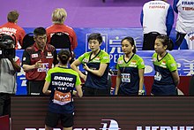 Four players standing listening to their coach.