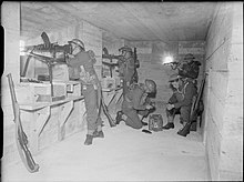 British soldiers man machine guns inside a concrete bunker.