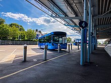 A two-tone blue single deck bus parked in an empty bus station.