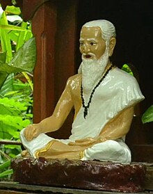Thai image of Jīvaka, in a white robe and bearded, wearing prayer beads around his neck