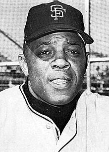 Photographic portrait of an older Willie Mays in a San Francisco Giants uniform, the top button of which is undone