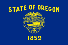 A navy blue flag with gold lettering and symbols; "STATE OF OREGON" is written above a shield, which is surrounded by 33 stars. "1859" appears underneath the shield.