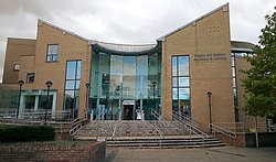 A modern yellow brick building with name "Rugby Art Gallery, Museum & Library", with a central glass entrance hall.