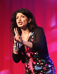 A woman holding one hand in front of her and holding a microphone in the other hand