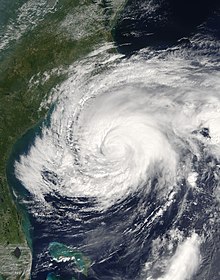 A satellite image of a weakening hurricane, with more translucent cloud tops to its south and west and whiter ones to the north and east.
