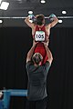 Gymnast graps the apparatus (here: horizontal bar), afterwards the coach steps back