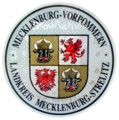 Zulassungsplakette des Landkreises Mecklenburg-Strelitz mit dem mecklen­burg-vorpommer­schen Landeswap­pen bis 2011
