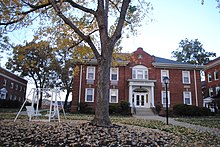A building marked with the name "Denmark Hall" on the right of the image, with a tree in the center and a white swing on the left.