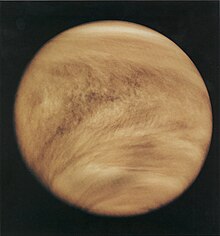 Light brown clouds wrap around a planet, as seen from space.