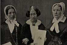 A black and white photo of three white women in Victorian clothing.