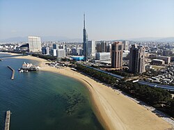 Aerial view of the seaside Momochi [ja] with the Fukuoka Tower and Momochi Seaside Park in the center and with the Fukuoka PayPay Dome to the left side