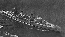 Three-quarter overhead view of cruiser with twin funnels and four gun turrets, at sea