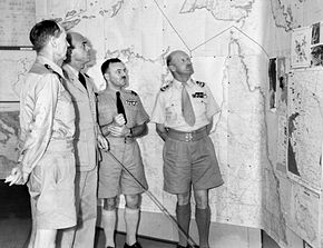 Four men in summer military uniforms in front of a map of northern Australia