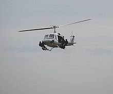 A helicopter flying with four special police troops standing on its landing skids