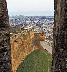 Photograph showing the wall at the Fortifications of Derbent with city buildings in the background