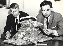 University students looking at coins collected from the fountain in 1965, with the large special cap on top of the coin bags