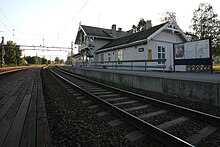 Foto eines Bahnhofs mit einem weiß gestrichenen Bahnhofgebäude