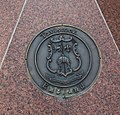 Coat of arms at sister city Celle (Germany), granite artwork below signpost