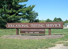 Large wooden sign with "Educational Testing Service" in white letters, on the law in front of ETS headquarters.