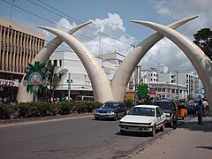Picture of the four white tusks, in two pairs each forming an arch, over a busy dual carriageway