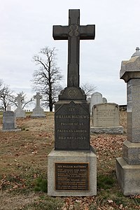 Gravestone in the shape of a cross with a plaque