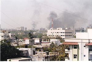 The image shows smoke rising from buildings and shops to the sky.