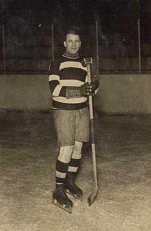 Gerard wearing skates and holding a hockey stick poses for a photo.