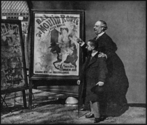 Zidler's assistant and Moulin-Rouge manager, Tremolada, pointing at Jules Chéret's 1889 poster, Bal du Moulin Rouge with Toulouse-Lautrec, Place Blanche, Paris, 1892[7]
