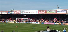 One of the stands of the Bootham Crescent association football ground, with supporters waving flags and a grass field below