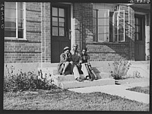 Three people sit on a step outside the Logan Fontenelle Housing projects in Omaha, Nebraska.