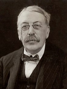 head and shoulders shot of an elderly man with full head of hair, moustache and pince-nez