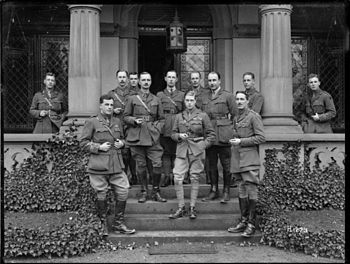Several men dressed as military officers standing on the verandah of a stone building