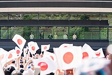 A group of people wave Japanese flags at the Imperial Palace.