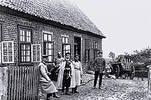 Charles Edward outside a building with four other men in German military uniforms