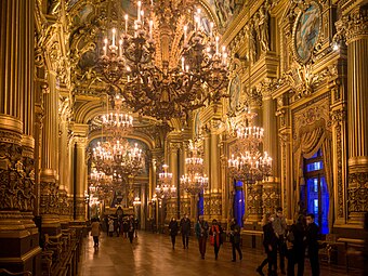 Grand foyer of the Palais Garnier, inspired by the Hall of Mirrors of the Palace of Versailles, but with some ornaments taken from other historical styles, like the neo-Renaissance column lower parts, or the Greek Revival lyres at the tops of windows, by Charles Garnier, 1860–1875[172]