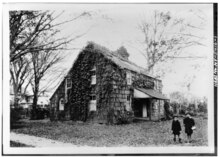 old photo of house with two children in the foreground to the right
