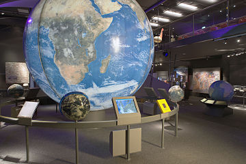 Exhibit with multiple globes of the earth, each conveying various information.