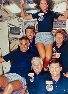 Resnik stands above her five male crewmates evoking a cheerleader pyramid.