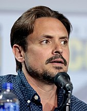 A photograph of Will Friedle in front of a microphone