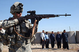 A U.S. soldier demonstrates shooting an M14 rifle to Iraqi Highway Patrol (IHP) police officers during training in Iraq, 2006.