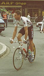 Photograph of Sean Kelly in black-and-white cycling uniform riding on his racing bicycle
