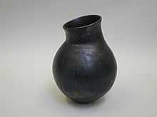 Burnished jar with asymmetrical mouth and neck (ridge beneath bend of neck). Black metallic finish, the result of burnishing and reduction firing.