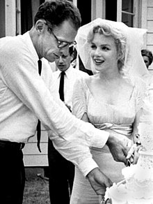 Arthur Miller and Marilyn Monroe standing, cutting a wedding cake