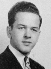 Ted Stevens in the Redondo High School Class of 1942 Yearbook. He has a dark suit, black hair, a neutral expression, and a striped tie.