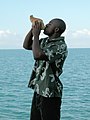 Man in olive Androsia blowing conch shell